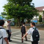 Personel Sat Lantas Polres Bima Kota Bantu Anak Sekolah Menyeberang Jalan